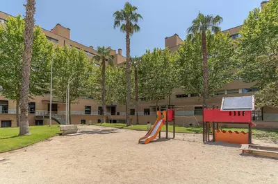 a playground in front of a building with palm trees at AB Olympic Village III Penthouse in Barcelona