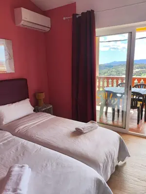 a bedroom with a bed and a balcony with a table at L'Olivera Casa Rural in Castellbisbal