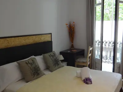 a bedroom with a white bed and a balcony at Hostal Balkonis in Barcelona