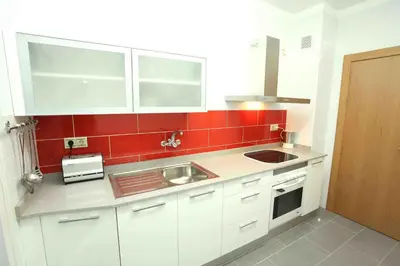 a small kitchen with white cabinets and red tiles at Bordeta in Barcelona