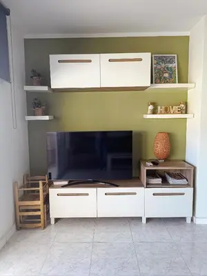 a living room with a large tv and white cabinets at Precioso Dúplex con terraza a 5 minutos playa y 20 minutos de Barcelona in Premiá de Mar