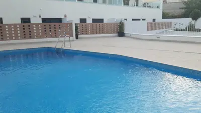 a large blue swimming pool next to a building at New beside Sitges with pool beside beach in Vilanova i la Geltrú