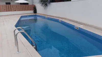a large blue swimming pool with a white wall at New beside Sitges with pool beside beach in Vilanova i la Geltrú