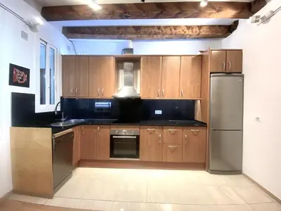 a kitchen with wooden cabinets and a stainless steel refrigerator at Ramblas Waterfront Stay in Barcelona