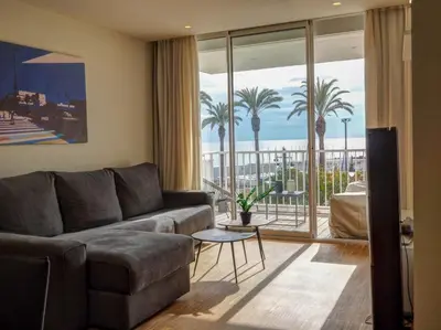 a living room with a couch and a balcony with palm trees at Paradise Apartment by Hello Homes Sitges in Sitges