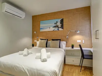 a bedroom with a large white bed and a desk at Paradise Apartment by Hello Homes Sitges in Sitges