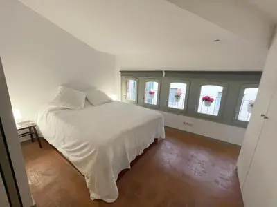 a bedroom with a bed with white sheets and windows at SG Apartamento céntrico ático in Terrassa