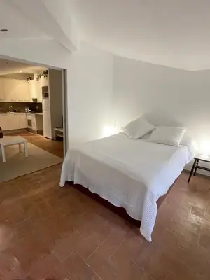 a bedroom with a white bed and a kitchen at SG Apartamento céntrico ático in Terrassa