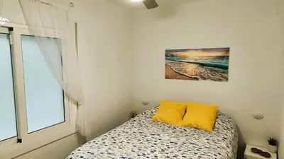 a bedroom with a bed with yellow pillows and a window at Canet playa y centro con free wifi in Canet de Mar