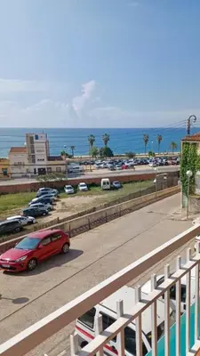 a red car driving down a road next to the ocean at Canet playa y centro con free wifi in Canet de Mar