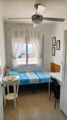 a bed in a room with a window and a table at Canet playa y centro con free wifi in Canet de Mar
