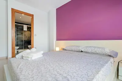 a bedroom with a large bed with a purple wall at Hauzify I Apartament Ponent in Pineda de Mar