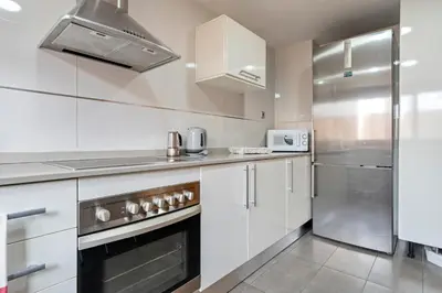 a kitchen with white cabinets and a stainless steel refrigerator at Hauzify I Apartament Ponent in Pineda de Mar