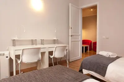 a white room with a desk and two beds at Enjoy Apartments VP Camp Nou 2 in Barcelona