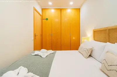 a bedroom with a white bed with a wooden closet at Flateli Pelayo H6 in Barcelona
