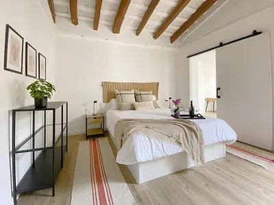 a white bedroom with a bed and a wooden ceiling at Historic House at Can Quintana by Casa de Elena in Pineda de Mar