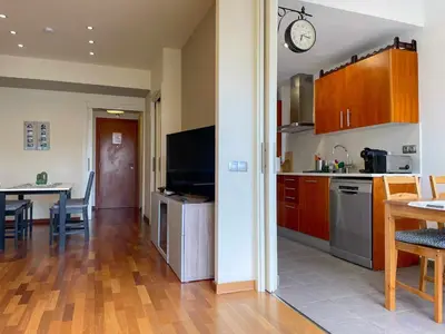 a kitchen and living room with a table and a clock at Apt Mediterreanea Parking Terrazza Netflix Hostem in Vilanova i la Geltrú