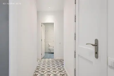 a bathroom with white walls and a toilet and a tile floor at Uma Suites Sagrada Familia in Barcelona