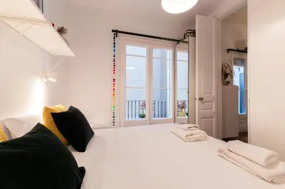 a bedroom with a white bed with a large window at Eixample Apartment in Barcelona