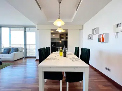 a dining room and living room with a white table and chairs at Forum Playa and Pool Barcelona in Barcelona