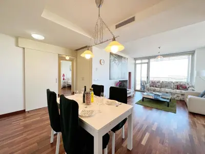 a dining room and living room with a table and chairs at Forum Playa and Pool Barcelona in Barcelona