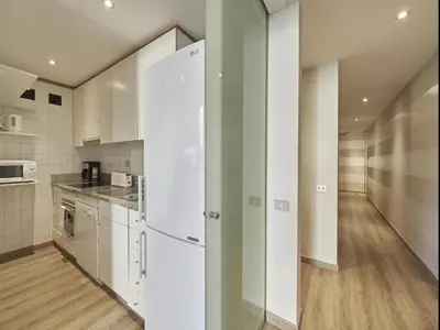 a kitchen with white cabinets and a white refrigerator at Gran Via Terrace Barcelona in Barcelona