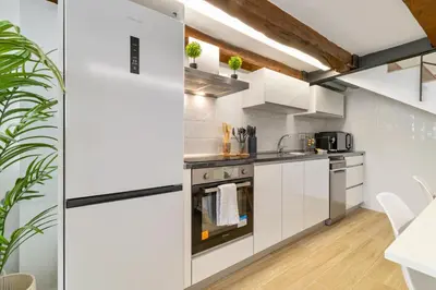 a kitchen with white cabinets and appliances and a ceiling at Nice Central Loft in Vilanova i la Geltrú
