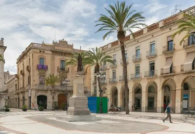 a man walking in front of a building with palm trees at Nice Central Loft in Vilanova i la Geltrú