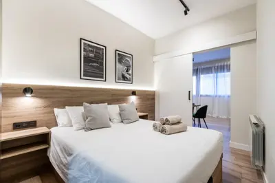 a bedroom with a large white bed and a chair at Exclusive Apartments Barcelona 4 personas St Pere in Terrassa