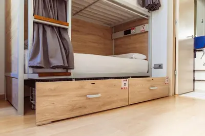 a bed in a room with wooden drawers at Leevin Student Barcelona in Barcelona