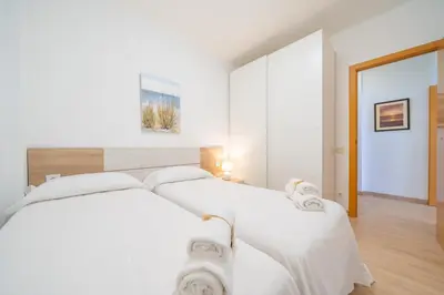 a white bedroom with a bed with white sheets at HomeHolidaysRentals Estrella - Costa Barcelona in Pineda de Mar