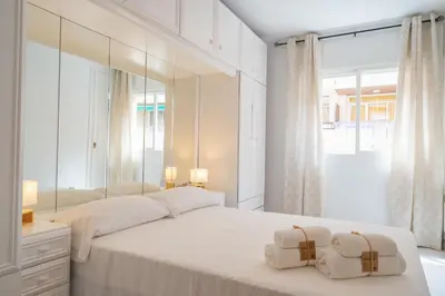 a bedroom with a large white bed with mirrors at HomeHolidaysRentals Caliz - Costa Barcelona in Pineda de Mar
