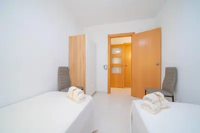 a room with two beds and two chairs in it at HomeHolidaysRentals Caliz - Costa Barcelona in Pineda de Mar