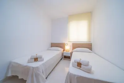 two beds in a white room with a mirror at HomeHolidaysRentals Caliz - Costa Barcelona in Pineda de Mar