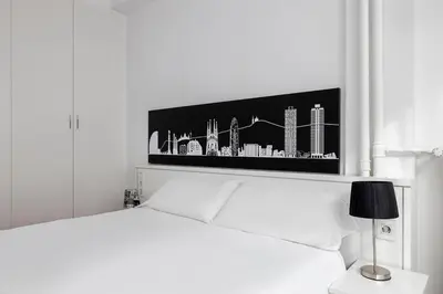a bedroom with a white bed with a picture on the wall at La Mejor Zona de Barcelona in Barcelona