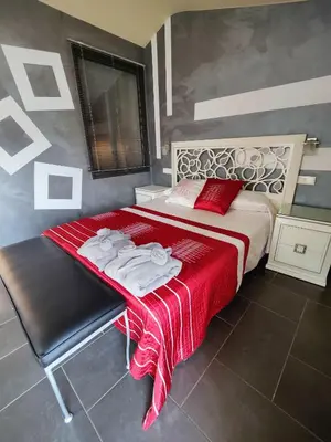 a bedroom with a bed with a red blanket on it at Hostal Manel in Pineda de Mar