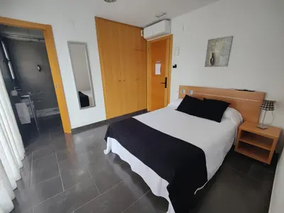 a bedroom with a large bed and a bathroom at Hostal Manel in Pineda de Mar
