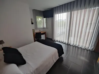a bedroom with a white bed and a large window at Hostal Manel in Pineda de Mar