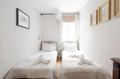 a bedroom with two beds with white sheets and a window at AB Paralel Blai Apartment in Barcelona