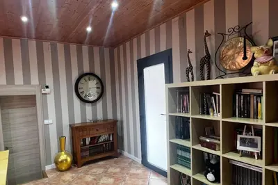 a room with a clock on the wall and a book shelf at Villa Oasis entre Viñedos cerca de Barcelona con A A y piscina climatizada in Caserío de Caʼn Rosell