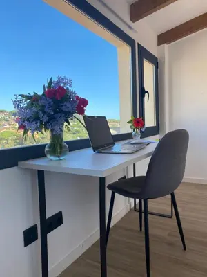 a desk with a laptop and a vase of flowers at Ses Voltes Boutique Home Sea and Sky in Vilassar de Dalt