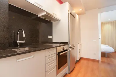 a kitchen with white cabinets and a stainless steel refrigerator at Rambla Suites in Barcelona