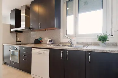 a kitchen with black and white cabinets and a sink at Espectacular piso cerca de la playa in Barcelona