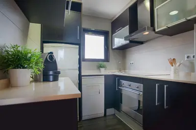 a kitchen with black cabinets and white appliances at Tendency Apartments 7 in Barcelona