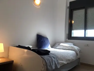 a bedroom with a bed with blue pillows and a window at New & Sunny Apartment in Barcelona