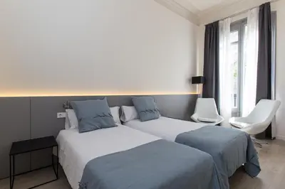 a hotel room with two beds and a chair at Izaila Plaza Catalunya in Barcelona