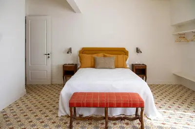 a bedroom with a white bed with a red stool at Bell Plançó B&B in Moià