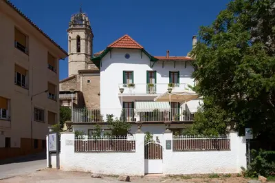 a white building with a clock tower in the background at Bell Plançó B&B in Moià