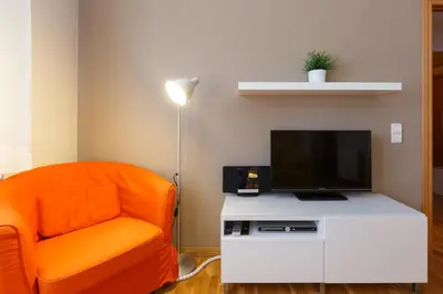 a living room with an orange chair and a flat screen tv at LetsGo Sagrada Familia Penthouse in Barcelona