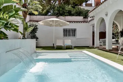 a swimming pool with an umbrella next to a house at Casa en Sitges in Sitges